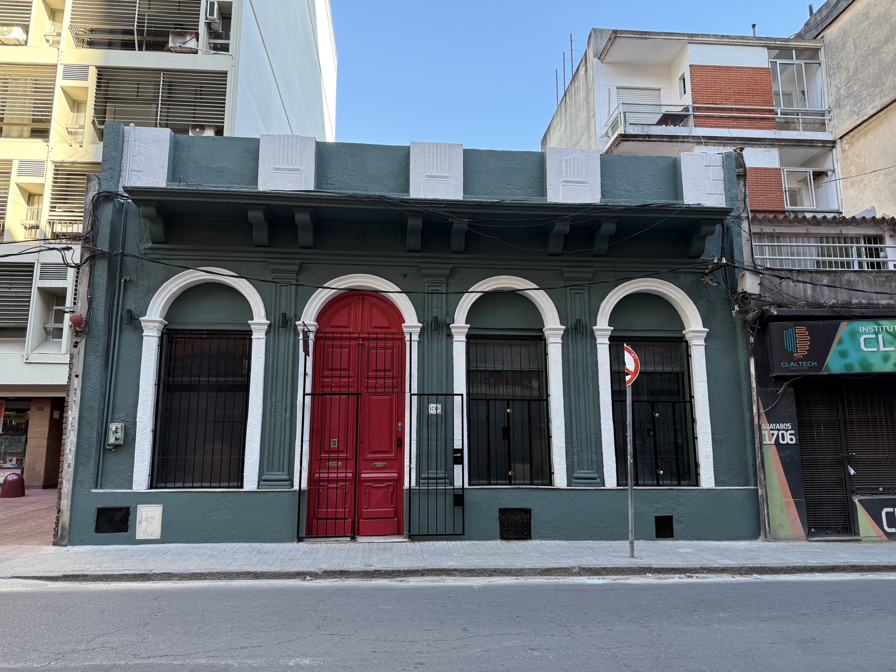 La casa de La Ruta en Guayabos 1710: fachada verde con arcos blancos y la puerta roja