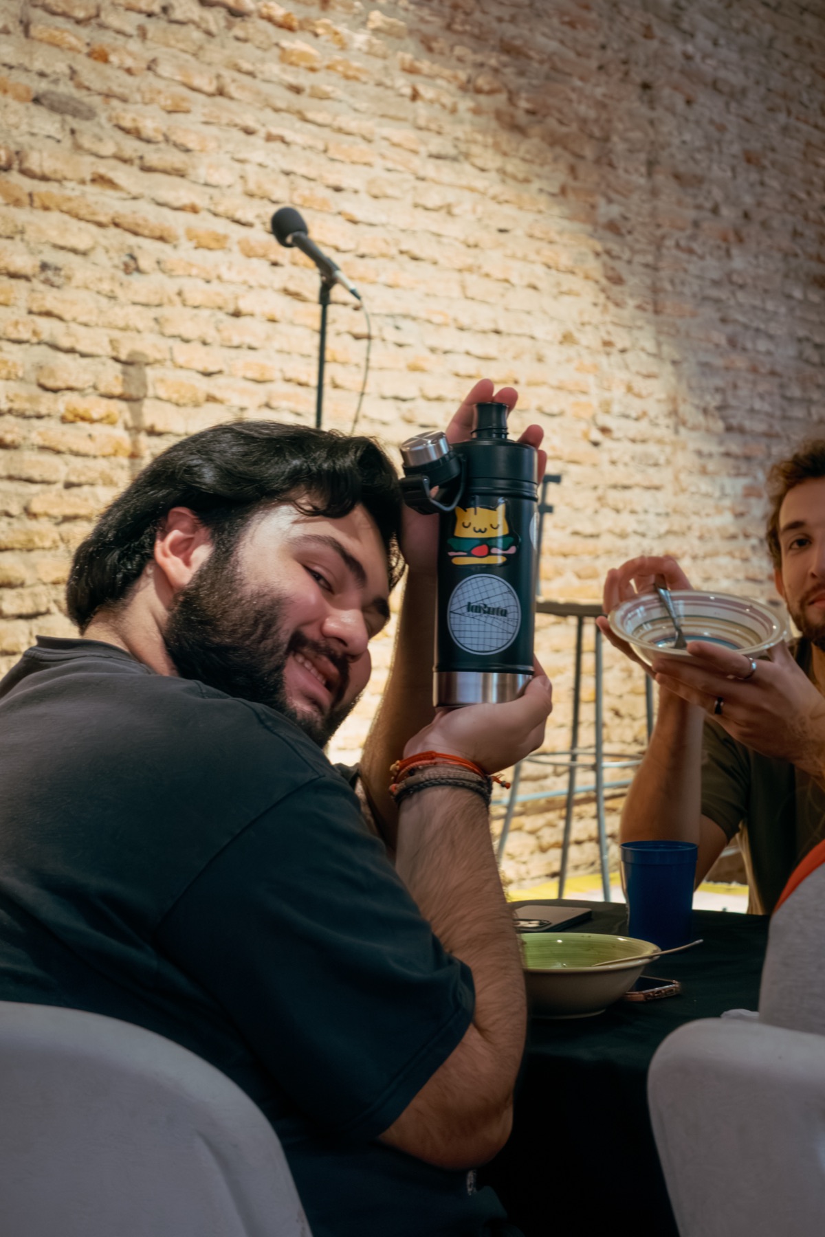 Un estudiante mostrando su termo de mate en un almuerzo